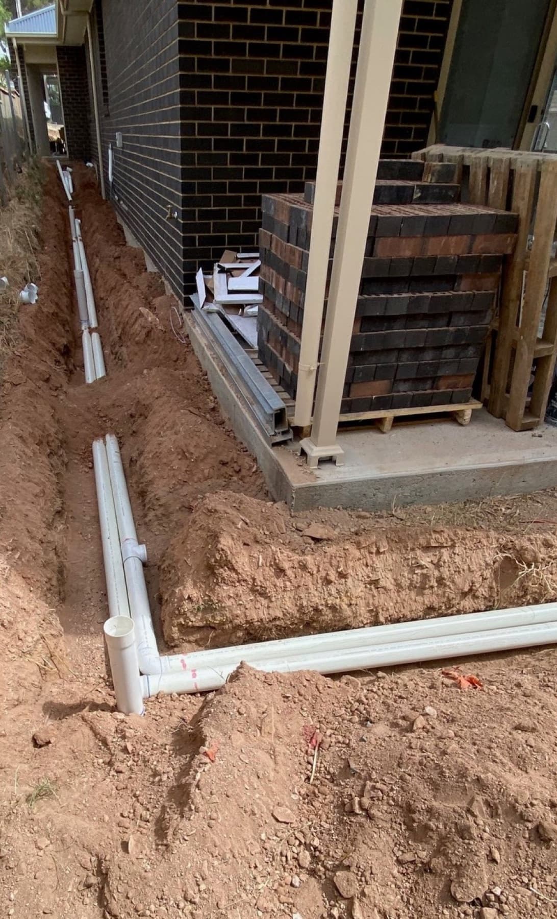 PVC stormwater pipes laid in foundation trenches at a new home construction site